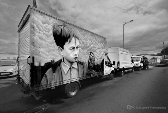 A black and white image shows artwork on the side of a van depicting a scene from the film Kes.