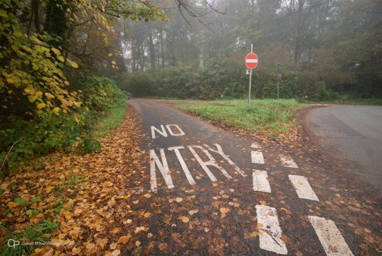A misty road junction with red no entry sign and no entry text on road